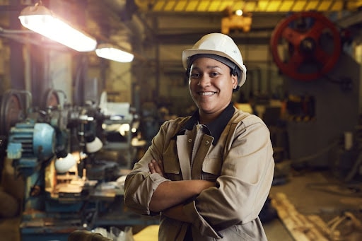 Black woman in a hard hat posing on a manufacturing floor
