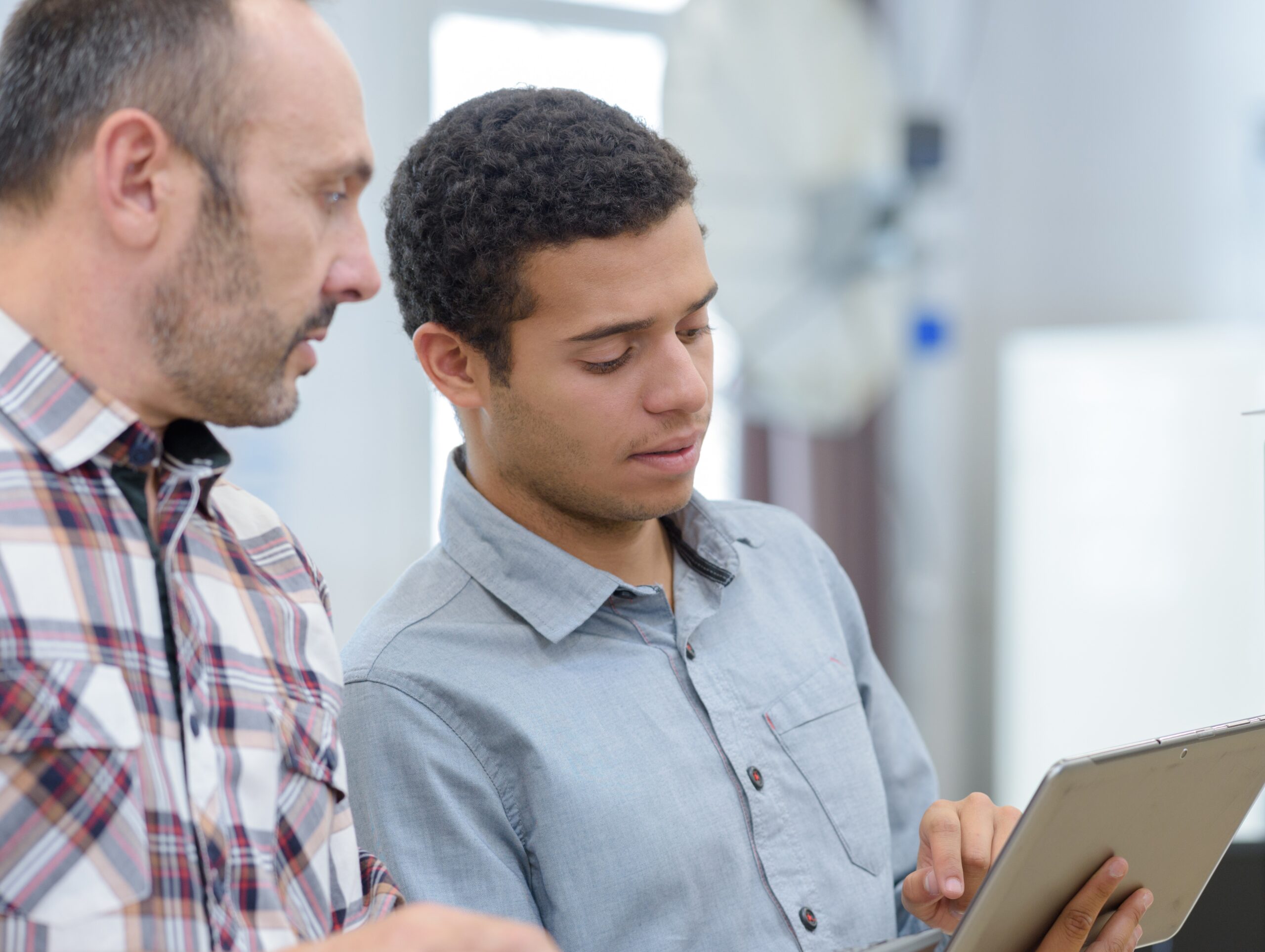 Manager helping entry level worker on tablet