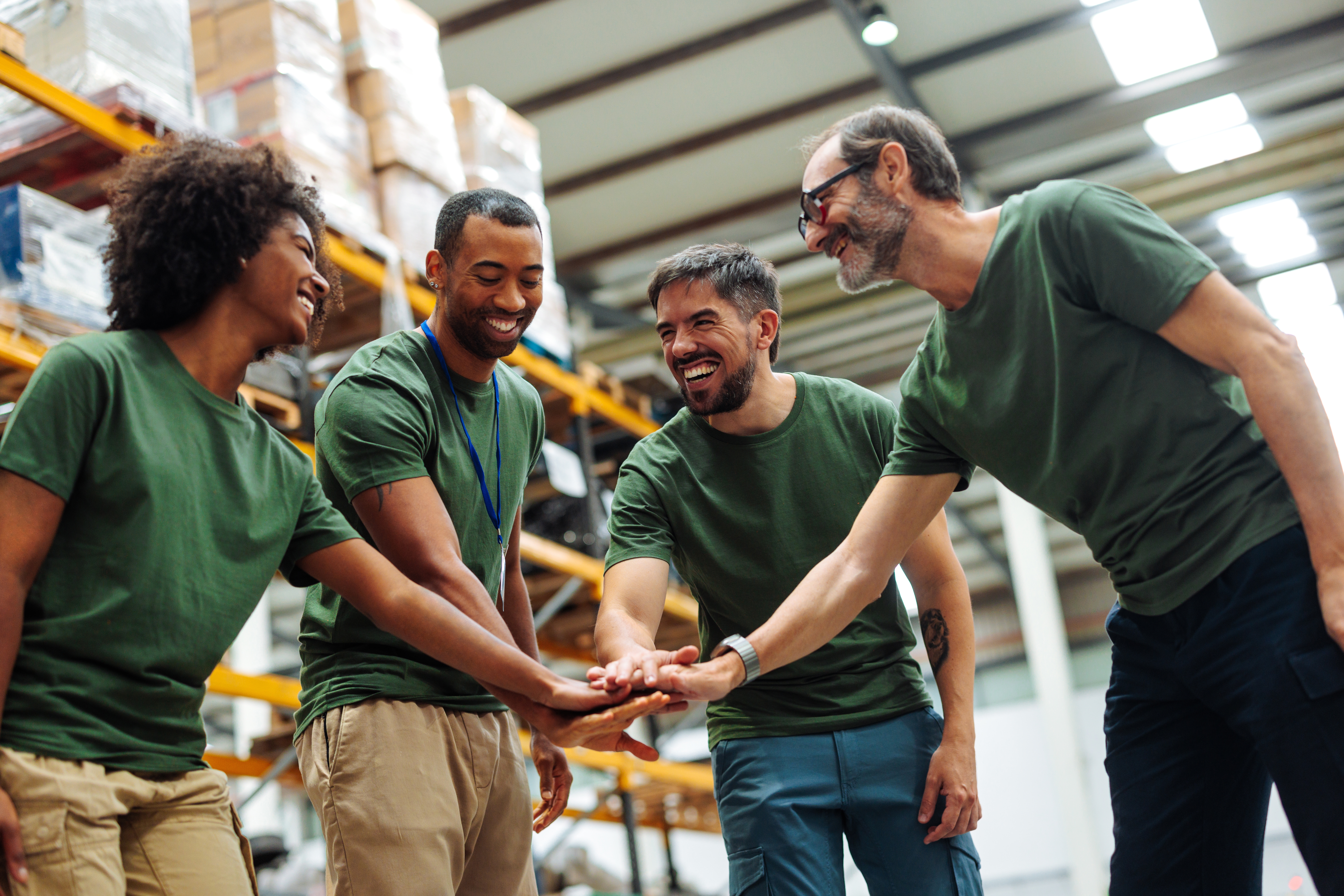 Diverse group of employees celebrating in warehouse, smiling